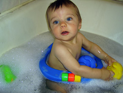 Kenji plays with a yellow rubber ducky in the bath.