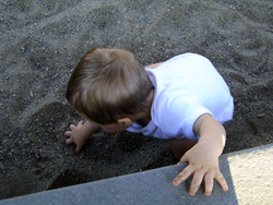 Kenji scoops sand at the park.